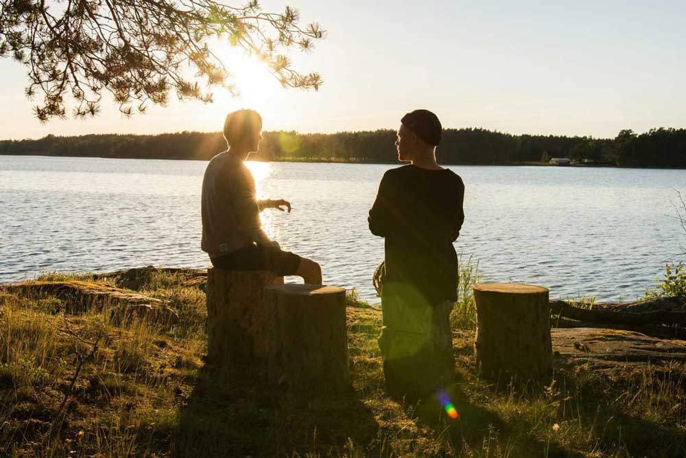 Two men talking next to a lake