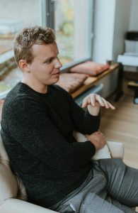 A shot of a man in the black cardigan talking from a 45 degree angle